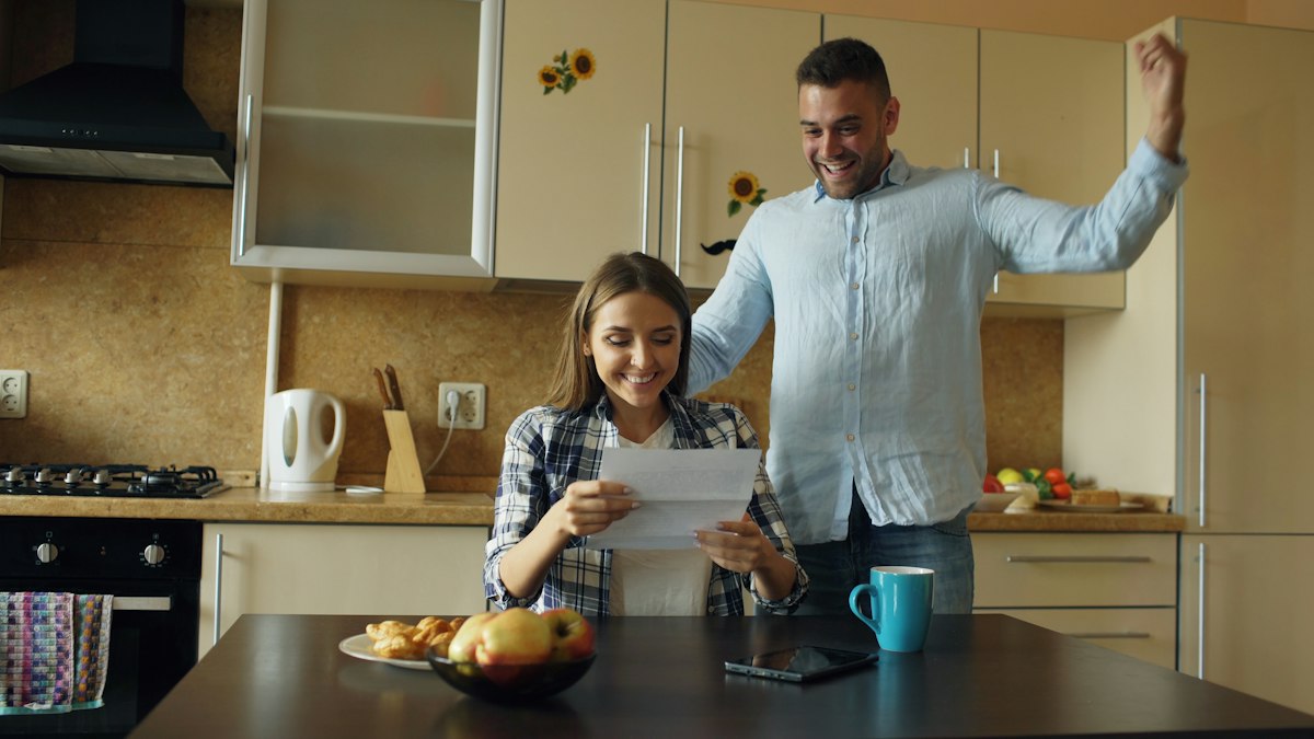 Couple celebrating good news about their finances in the kitchen