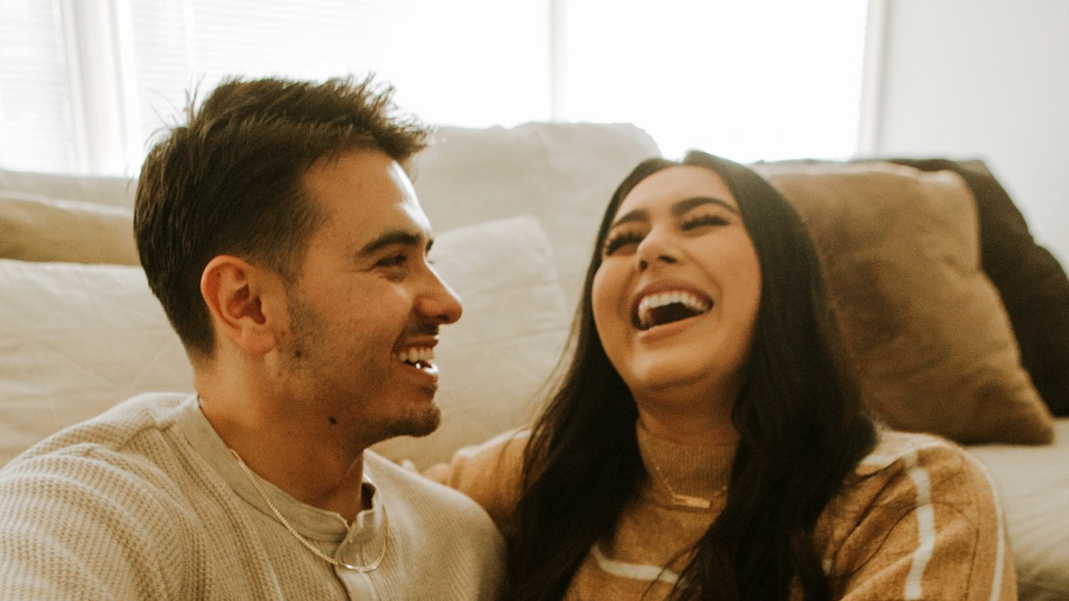 Young couple laughing together on a sofa at home