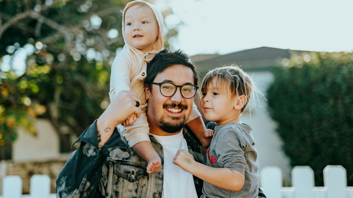 Smiling father carrying his young daughter at home