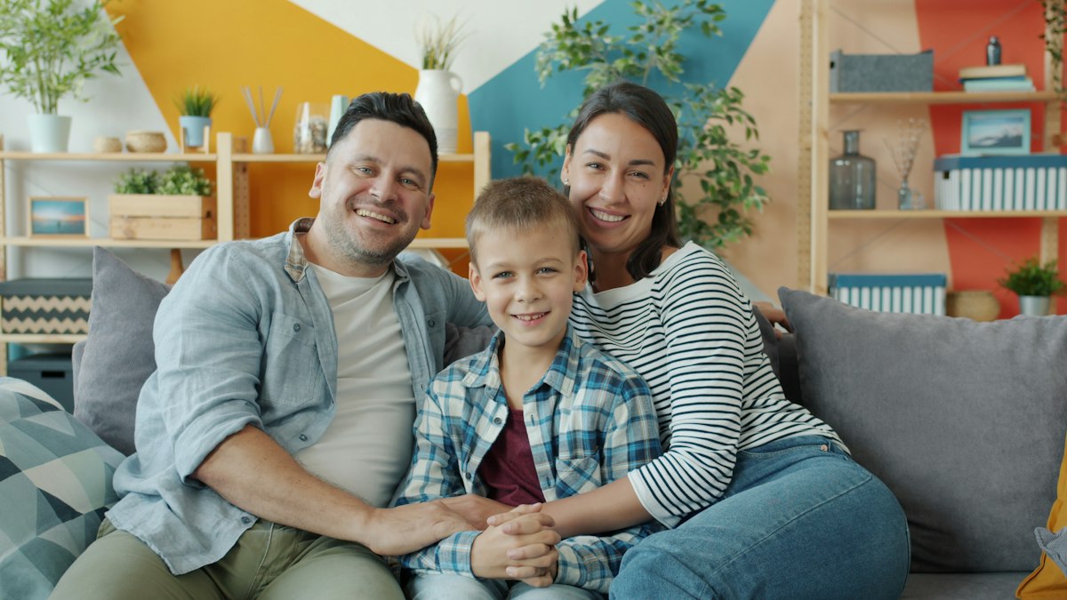 Smiling family of three relaxing together on a couch at home