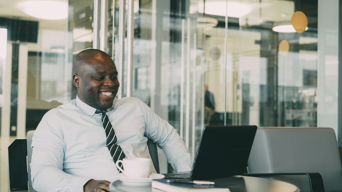 Smiling man reviewing a loan offer on his laptop with a coffee