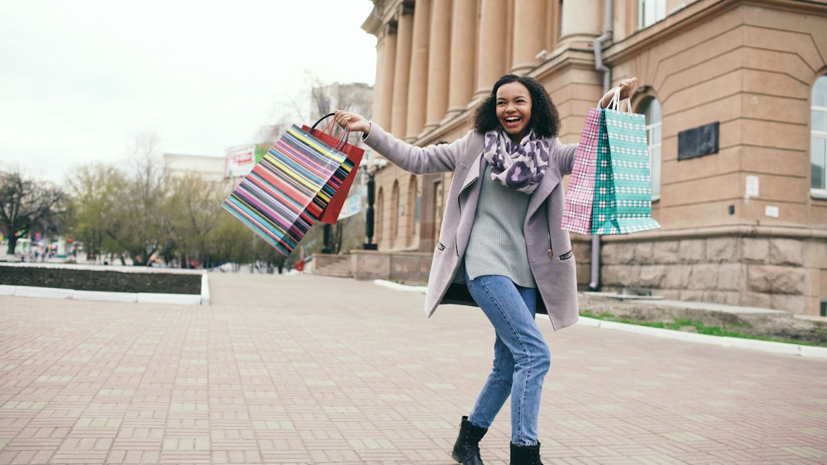 Woman happily holding shopping bags outside a store